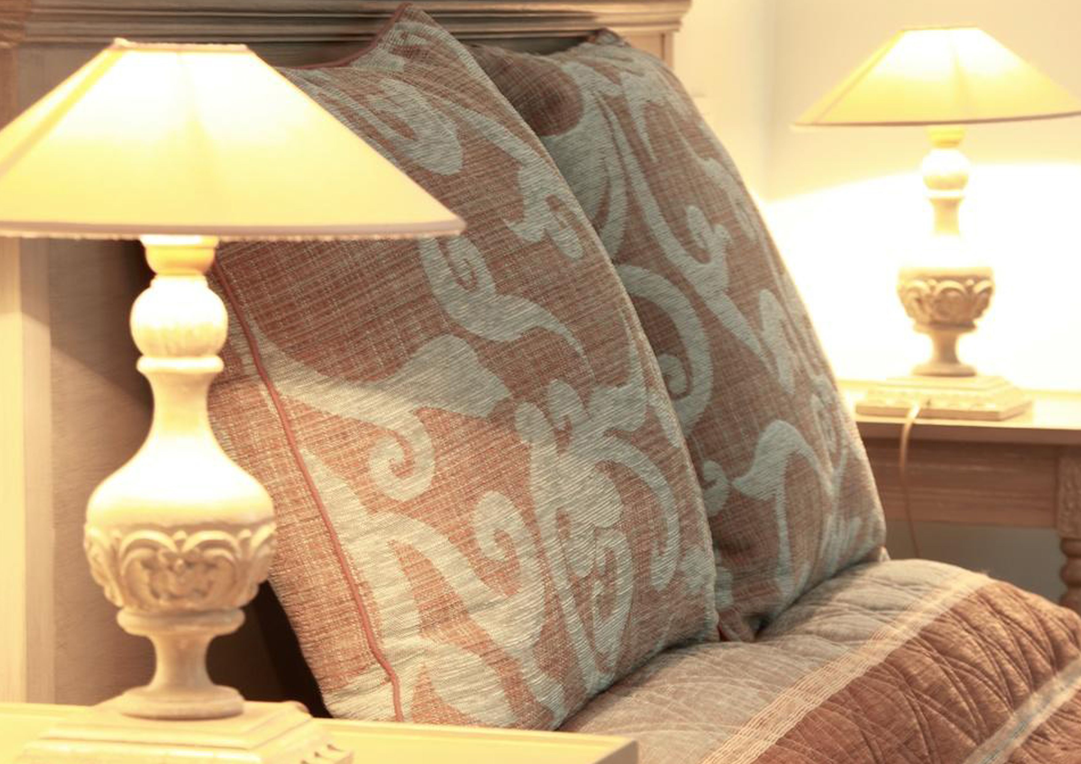 Een bed met twee decoratieve kussens en twee bedlampjes.