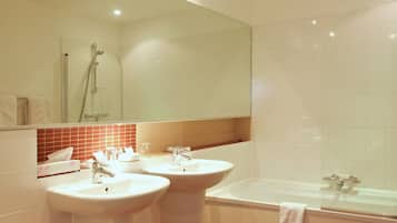 Une salle de bain moderne avec deux lavabos, une baignoire et une douche.
