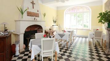 A dining area with a checkered floor, white chairs, and tables set for dining.