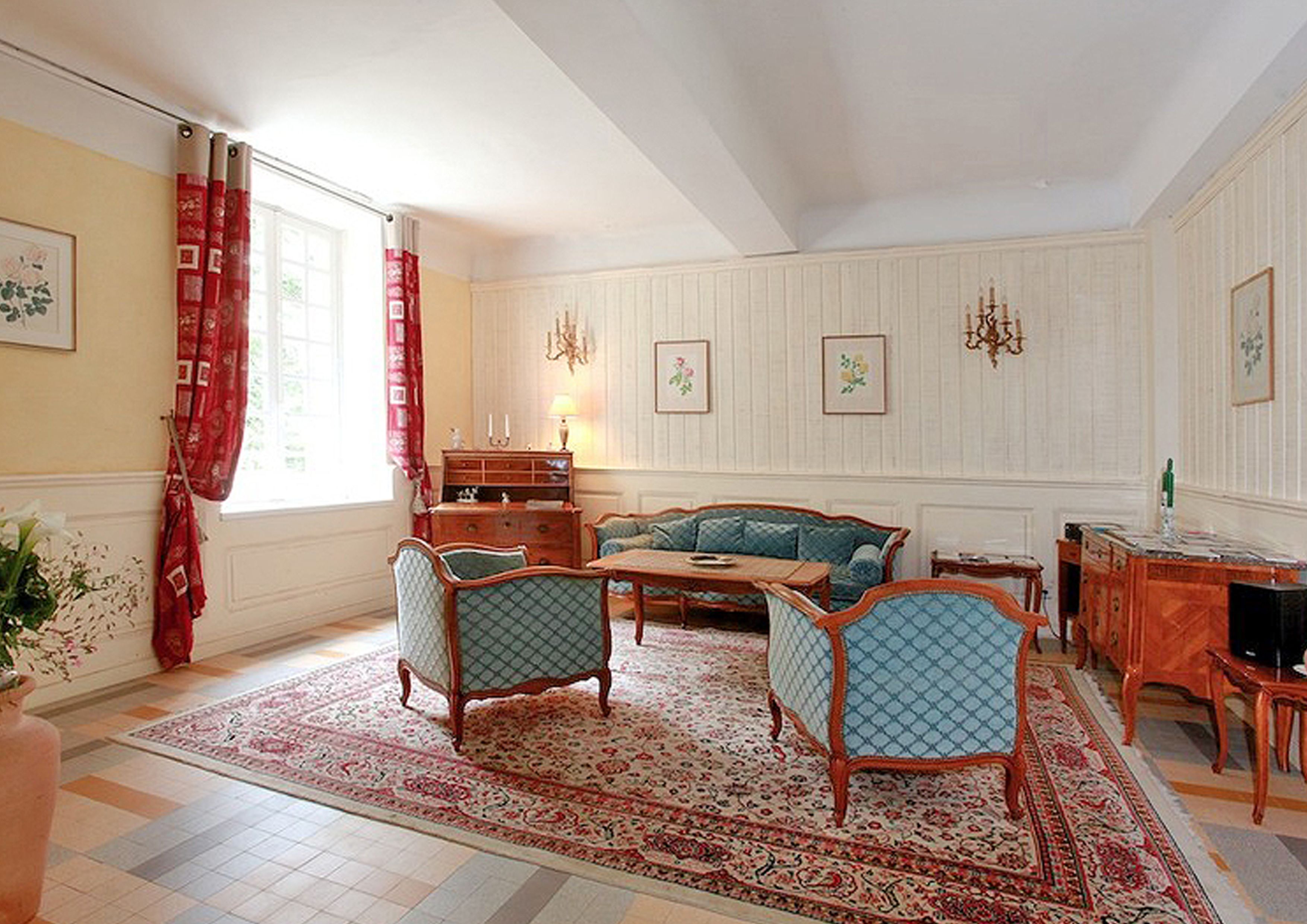 A traditional living room with a sofa, chairs, a wooden coffee table, and a patterned rug.