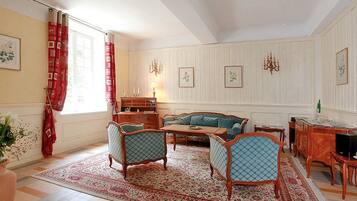 A traditional living room with a sofa, chairs, a wooden coffee table, and a patterned rug.