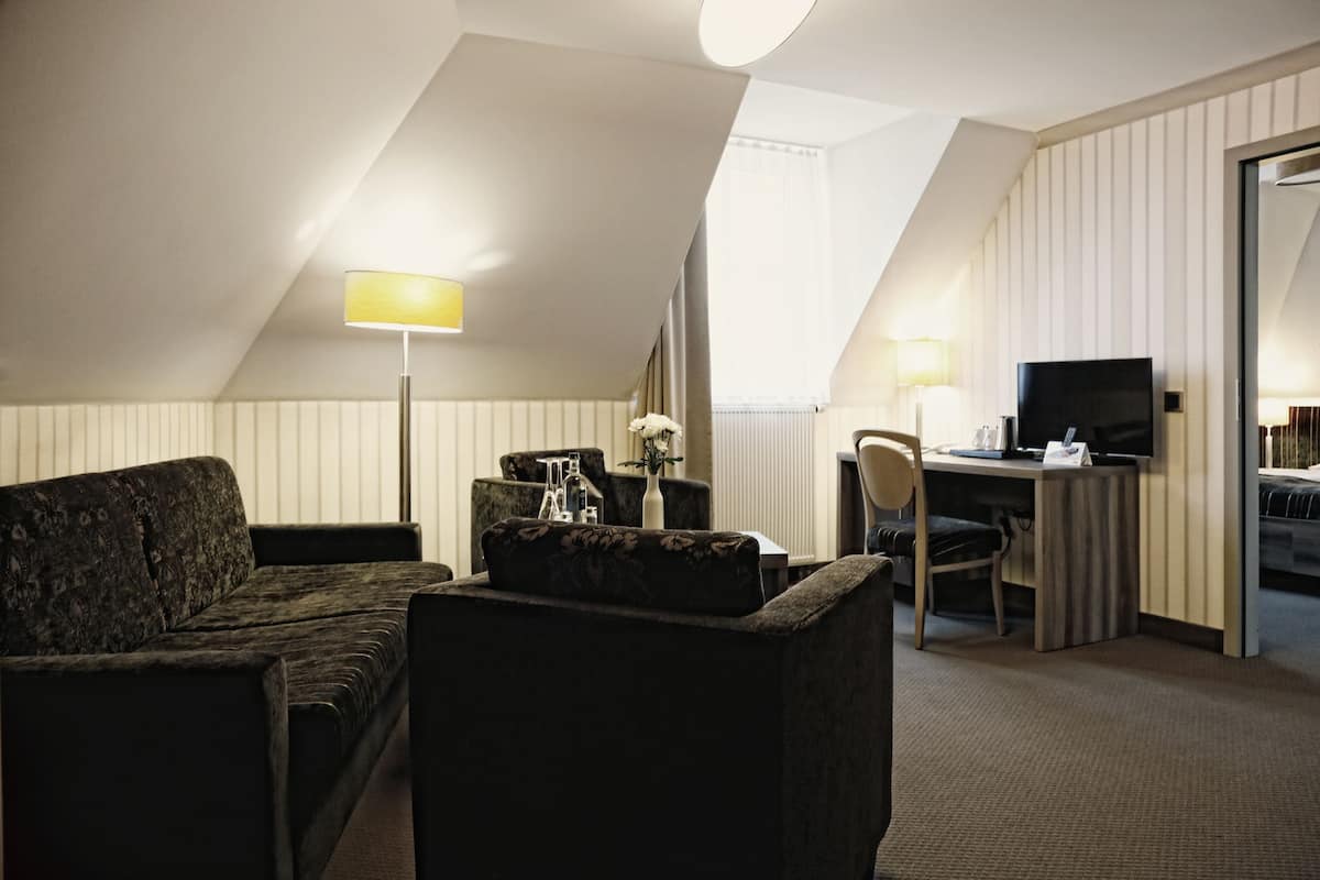 Une chambre d’hôtel équipée d’un canapé, d’un bureau, d’une chaise, d’une télévision et d’une lampe.