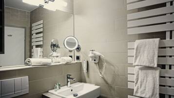 A modern bathroom with a sink, mirror, towel rack, and a hairdryer.