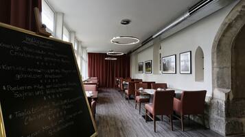 Een restaurant met lange tafels, een krijtbordmenu en ingelijste foto’s aan de muur.