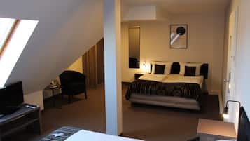 A hotel room with a bed, a desk with a television, a chair, and a small table.