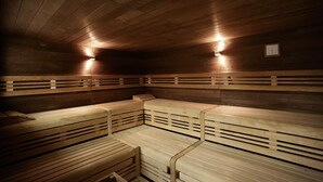 A sauna with wooden benches and slatted backrests, equipped with wall-mounted lighting.