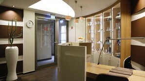 A modern interior with a reception desk, a clock, a plant, and a glass display cabinet.