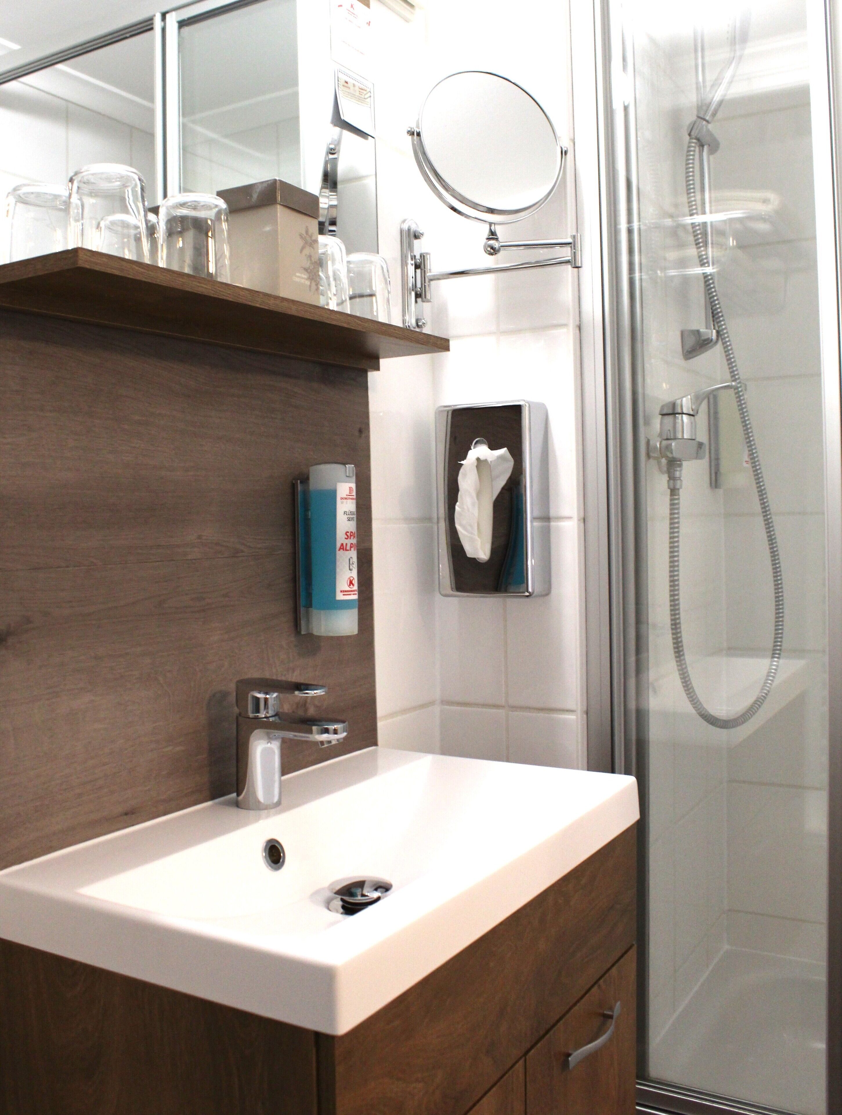 Un baño con lavamanos, espejo y ducha.