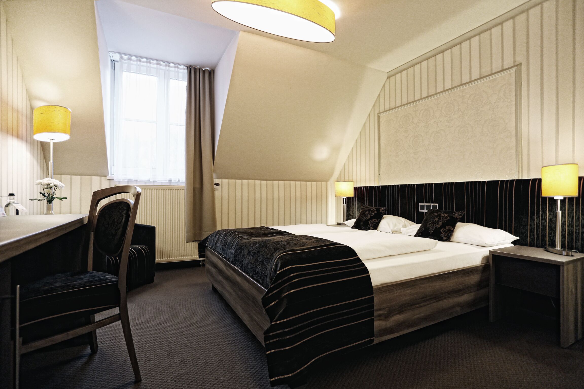 Ein Hotelzimmer mit einem Bett, Nachttischen, einem Schreibtisch und einem Sessel.