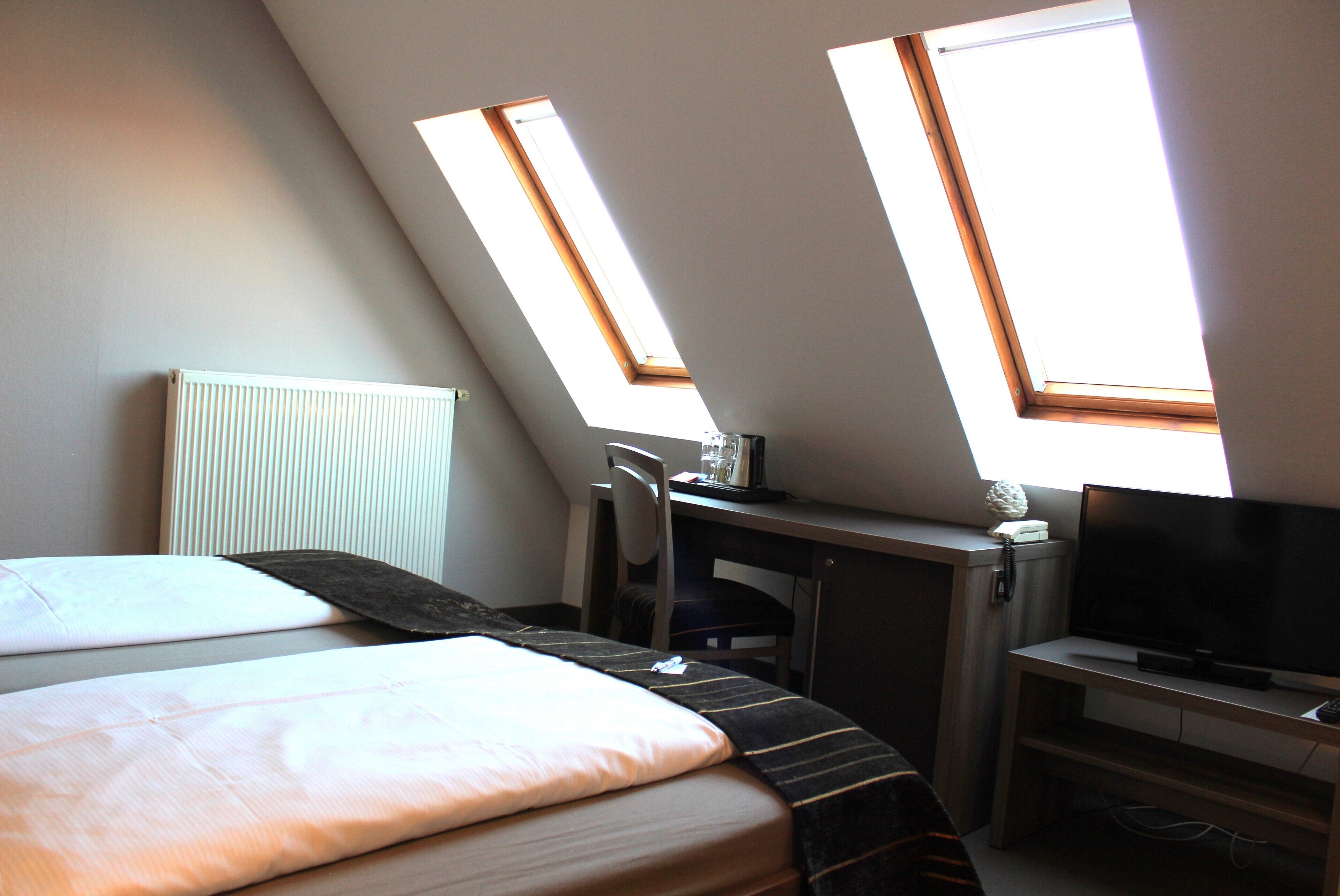 Une pièce comprenant un lit, un bureau, une chaise, un téléviseur et des fenêtres de toit.
