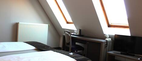 Une pièce comprenant un lit, un bureau, une chaise, un téléviseur et des fenêtres de toit.