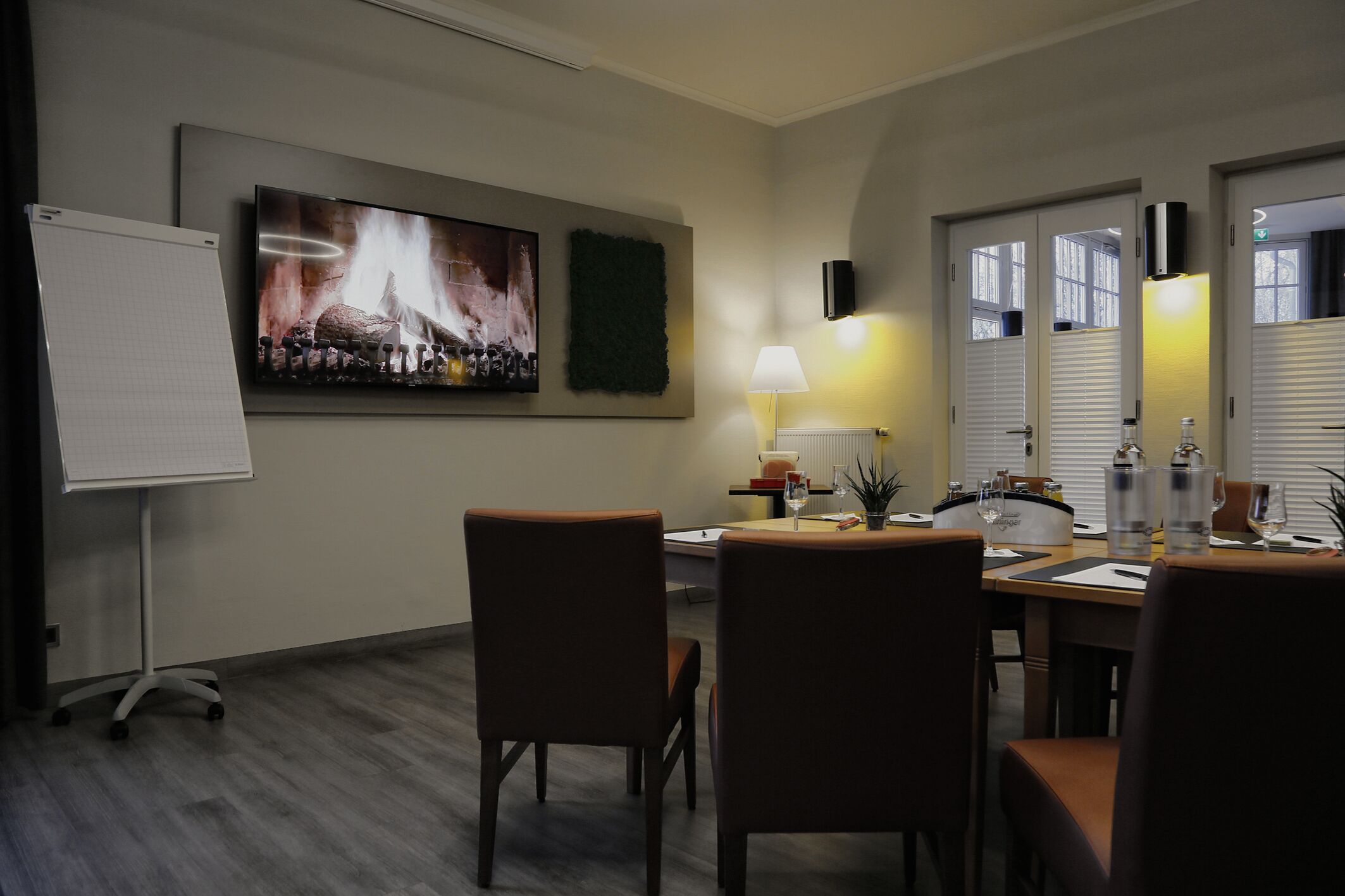 Ein Konferenzraum mit einer Tafel, einem großen Gemälde, einem Tisch mit Stühlen und einer Lampe.