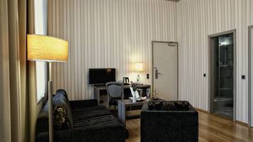 Una habitación de hotel moderna con sofá, sillón, escritorio y televisor.