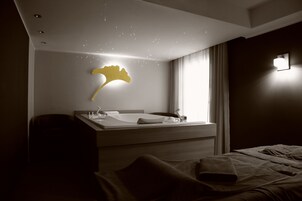 Una habitación de hotel moderna con una cama grande, una mesita de noche, un espejo y una lámpara fijada a la pared.
