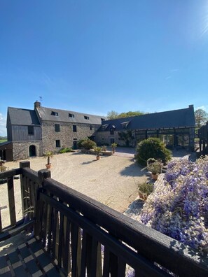 A stone building with a courtyard, potted plants, and a wooden fence. - Manoir de Rigourdaine (Plouer-sur-Rance)
