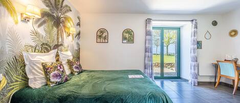 Un dormitorio con colcha verde, un mural de palmeras y vistas al exterior a través de un ventanal.