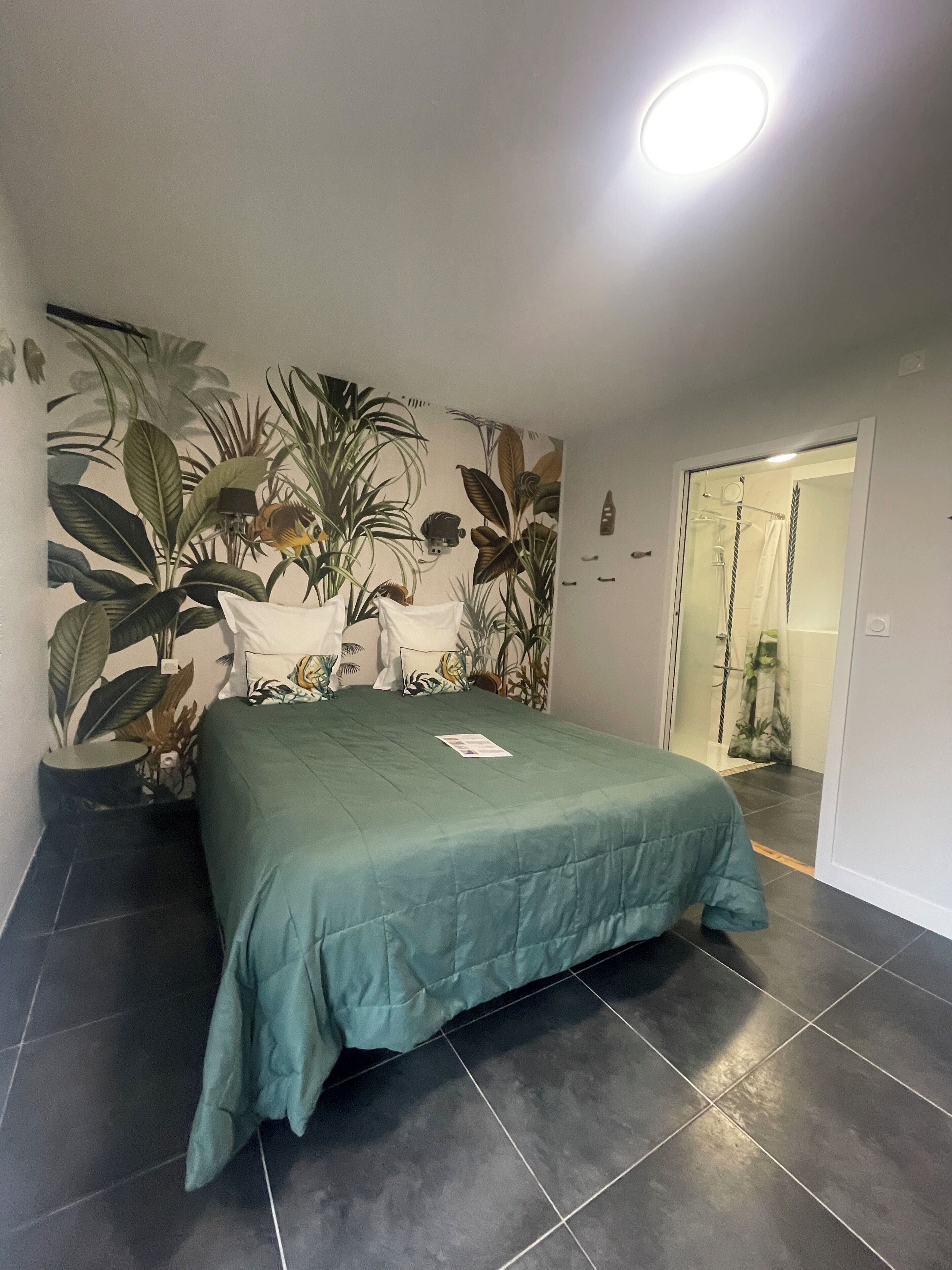 Een slaapkamer met een bed, een potplant en een douchehoek.