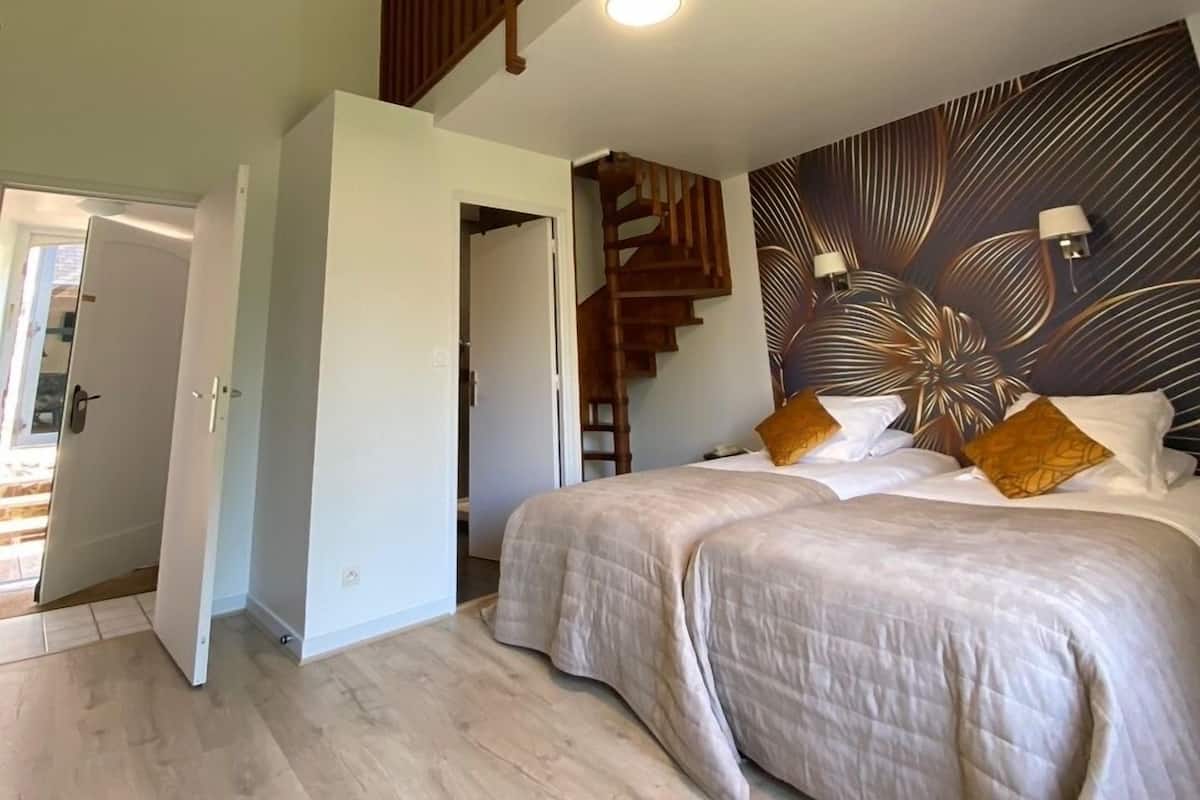 A spacious bedroom with a large bed, a wooden staircase, and a modern wall design.