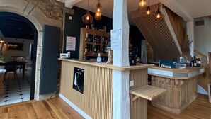 A bar area with wooden flooring, a counter with a logo, and hanging light fixtures. - Manoir de Rigourdaine (Plouer-sur-Rance)