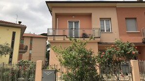 A two-story residential building with a balcony, a gated entrance, and a small garden with flowering plants. - Affittacamere Le Rose (Imola)