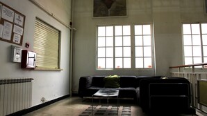 A room with a radiator, a black sofa, a small table, and a window with blinds. - Hostal Al-Andalus (Granada)