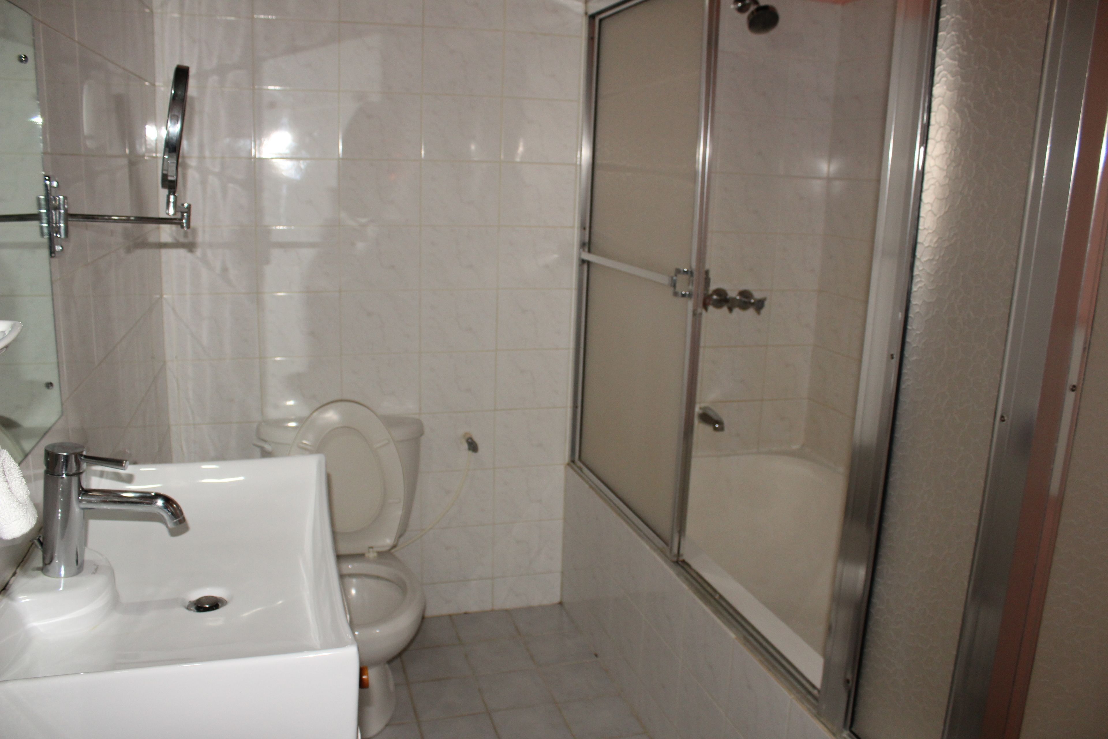 A bathroom with a sink, toilet, and a glass-enclosed shower area.