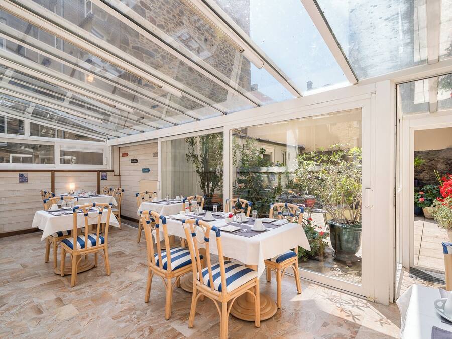 A conservatory with tables and chairs, a stone floor, and a view of the garden.