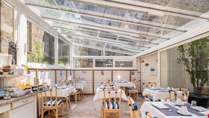 A restaurant with a glass roof, wooden chairs, and tables set for dining. - Hôtel Quic en Groigne (Saint-Malo)