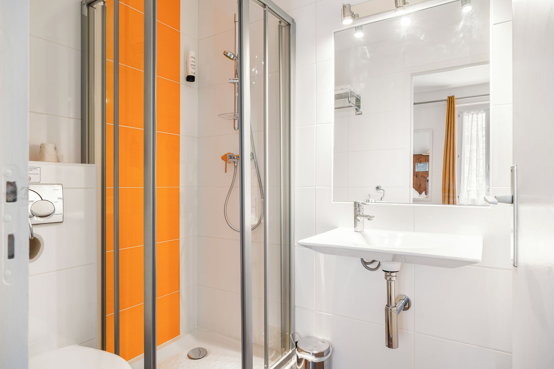 A modern bathroom with a glass-enclosed shower, a white sink, and a mirror.