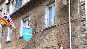A hotel building with stone walls, multiple windows, and flags. There are signs indicating the hotel name and a no parking sign. - Hôtel Quic en Groigne (Saint-Malo)