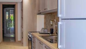 A modern kitchen with light wood cabinets, a built-in oven, and a refrigerator. - Milonas House Apartments (Nea Propontida)