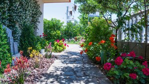 A stone pathway leading to a white building with a sign reading "Milonas House". - Milonas House Apartments (Nea Propontida)