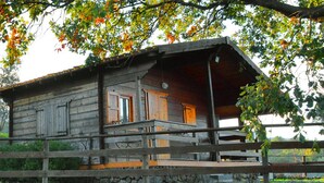 Eine rustikale Holz-Blockhütte mit einem Balkon, umgeben von einer Steinmauer und üppigem Grün.