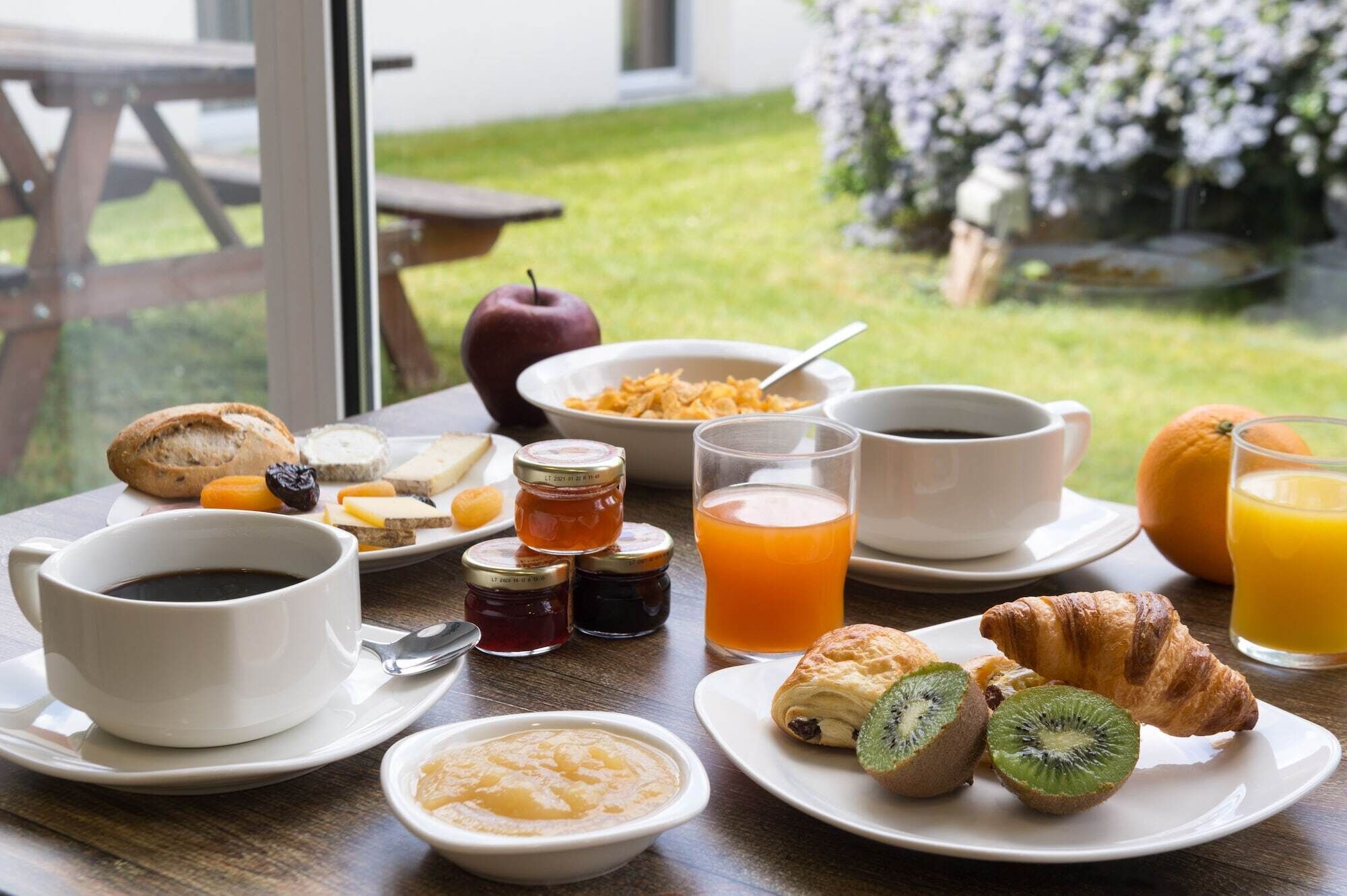 Una mesa de desayuno con diversos alimentos, como pasteles, frutas y bebidas.