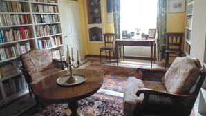 A cozy living room with a fireplace, a bookshelf, a dining table, and two armchairs. - Maison Sans Soucis (Sainte-Gemme)