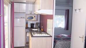 A compact kitchenette with a microwave, coffee maker, and sink. - Camping les Terrasses de Rivarennes (Rivarennes)
