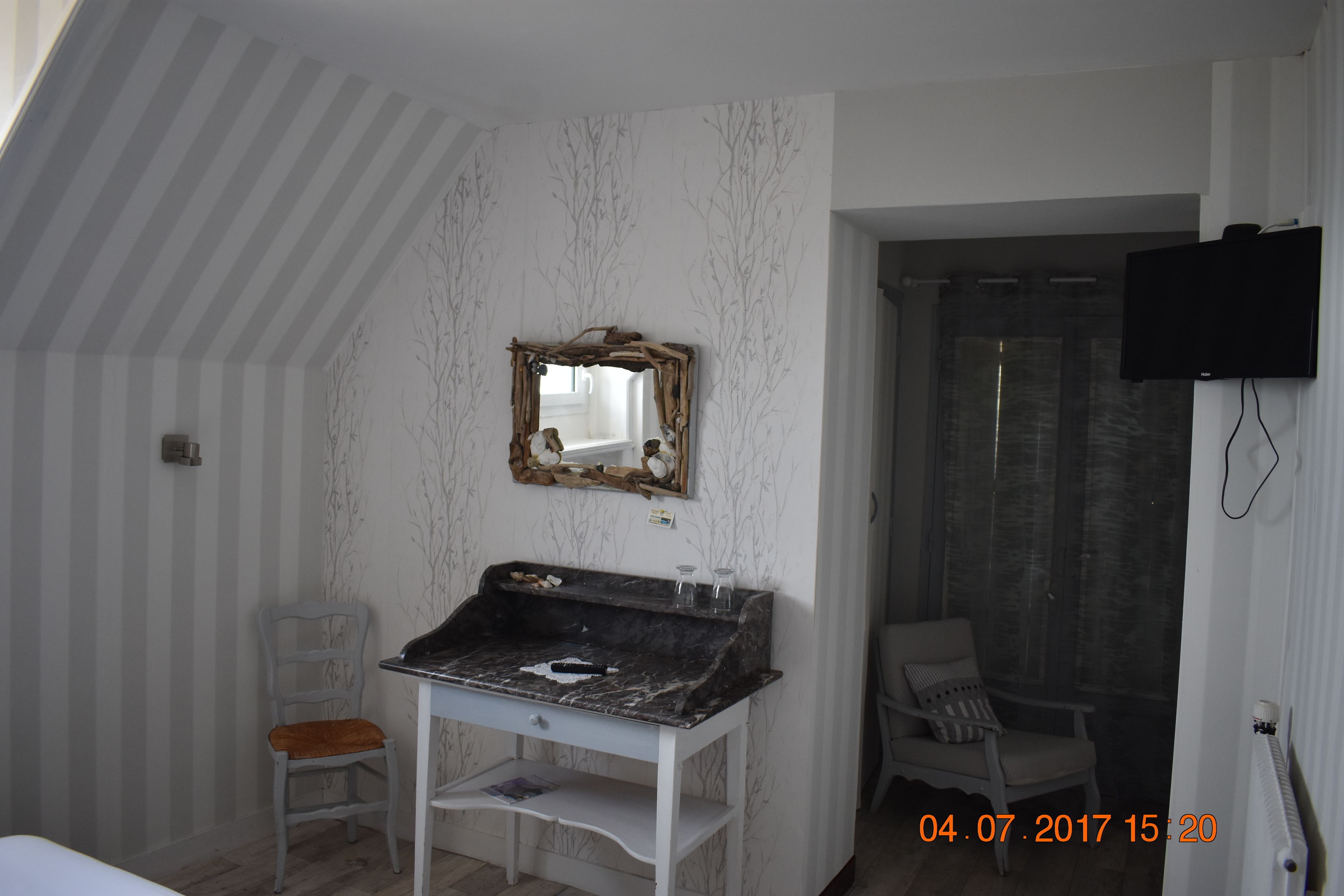 A bathroom with a vanity, mirror, shower, and a television mounted on the wall.