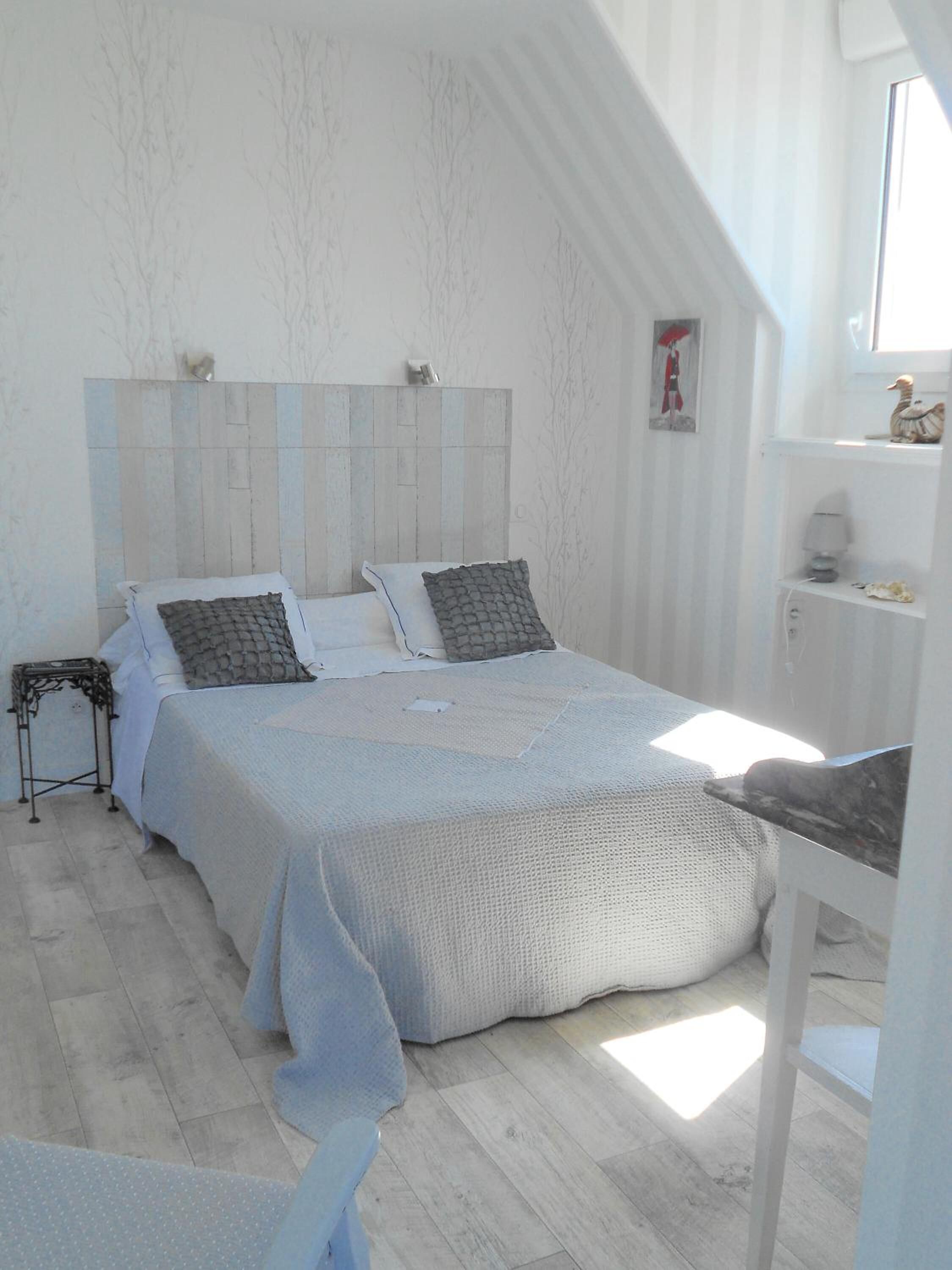 Une chambre avec un grand lit, une table de chevet et une fenêtre.