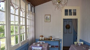 Un comedor con una mesa preparada para el té, una araña y una puerta decorada con un adorno.