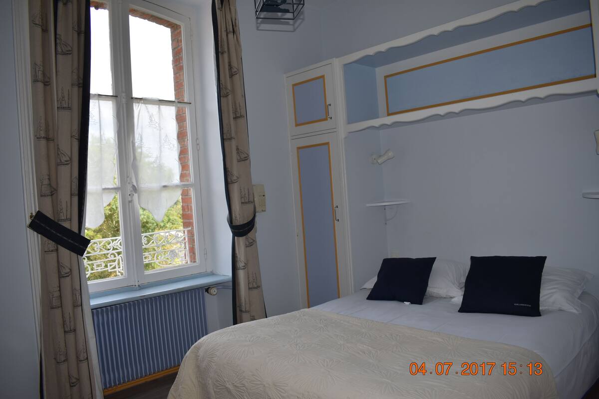 A bedroom with a bed, curtains, a window, and a radiator.
