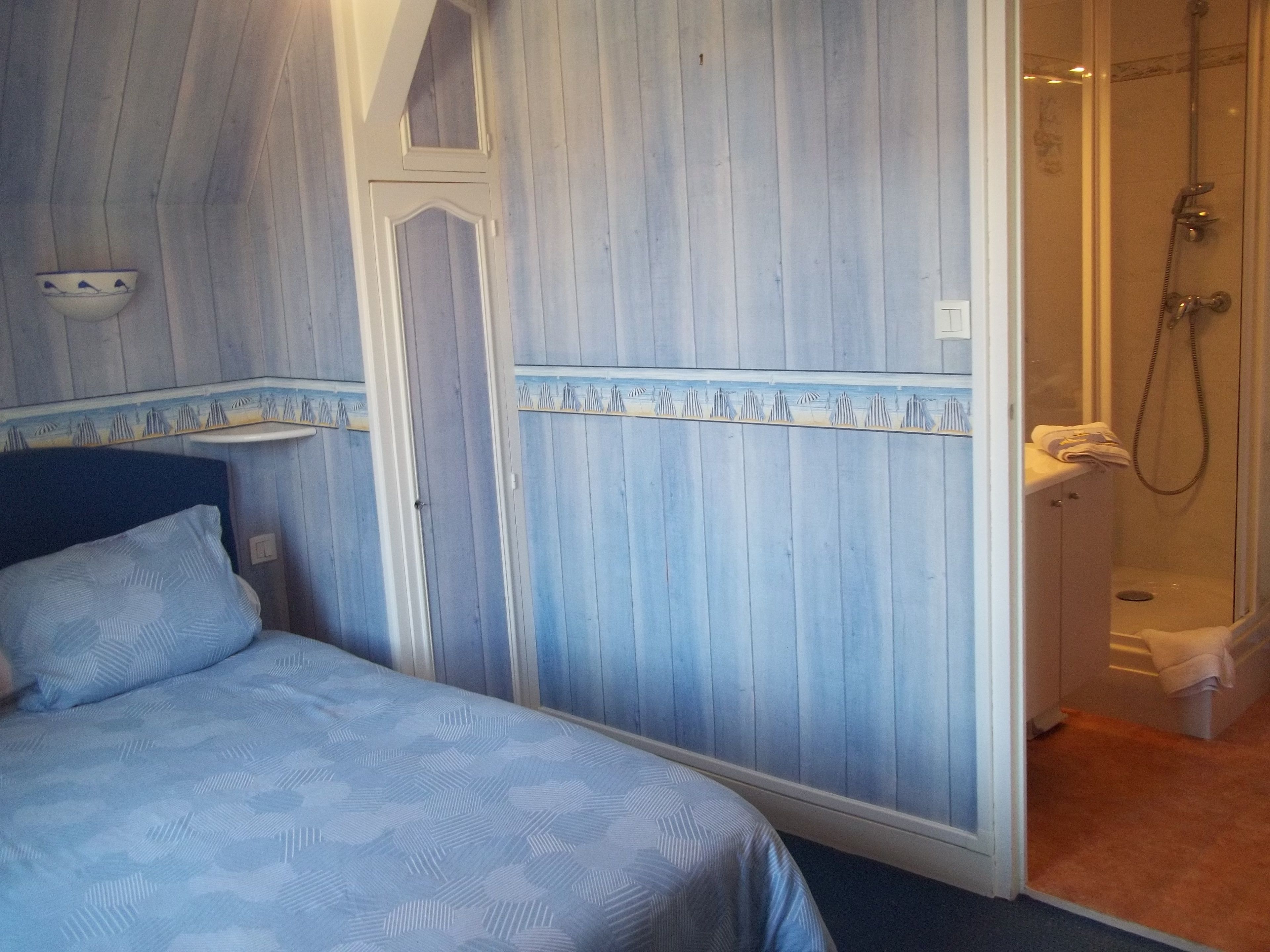Un dormitorio con cama, armario y zona de ducha.