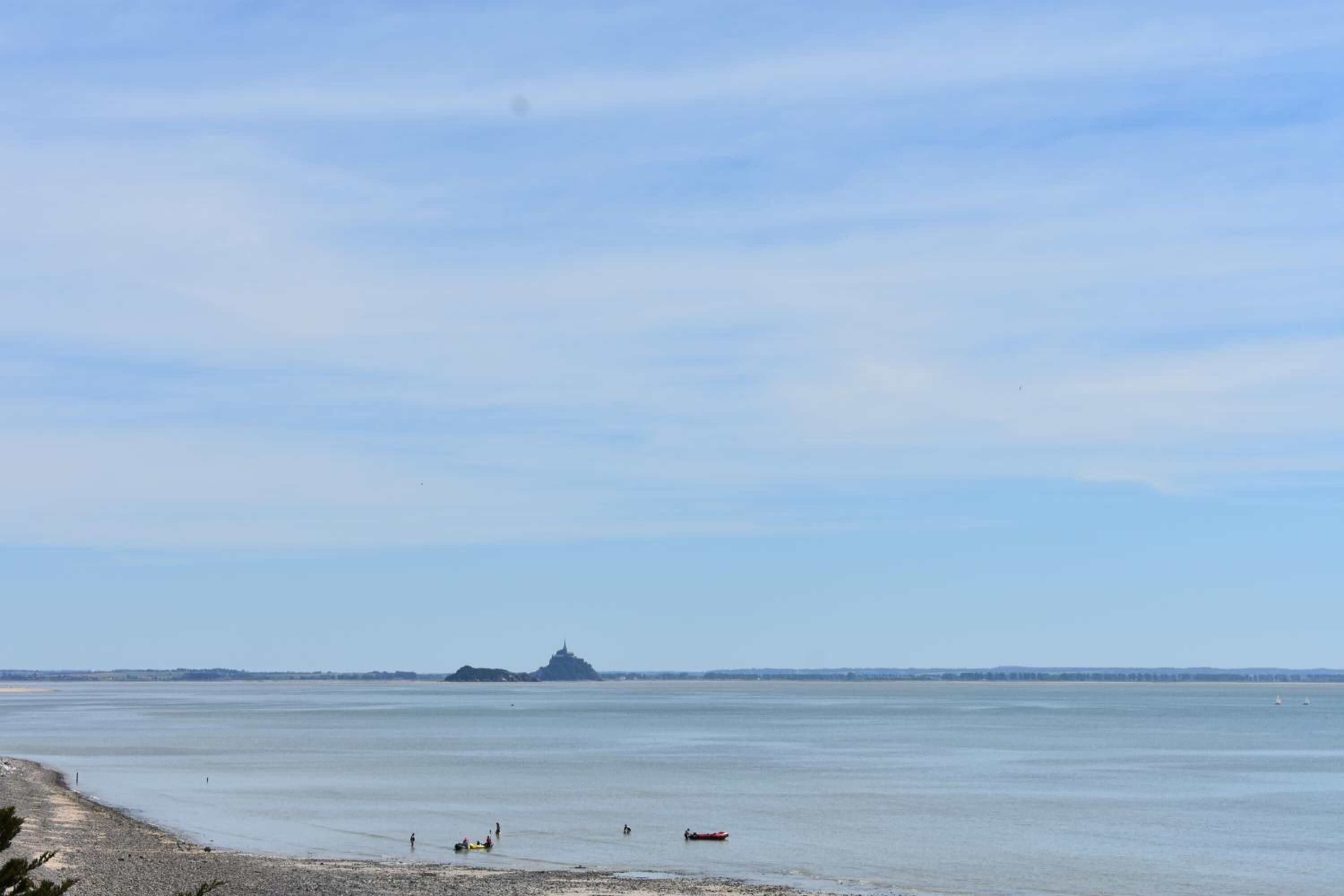 A coastal view with a beach, calm water, and a distant island.