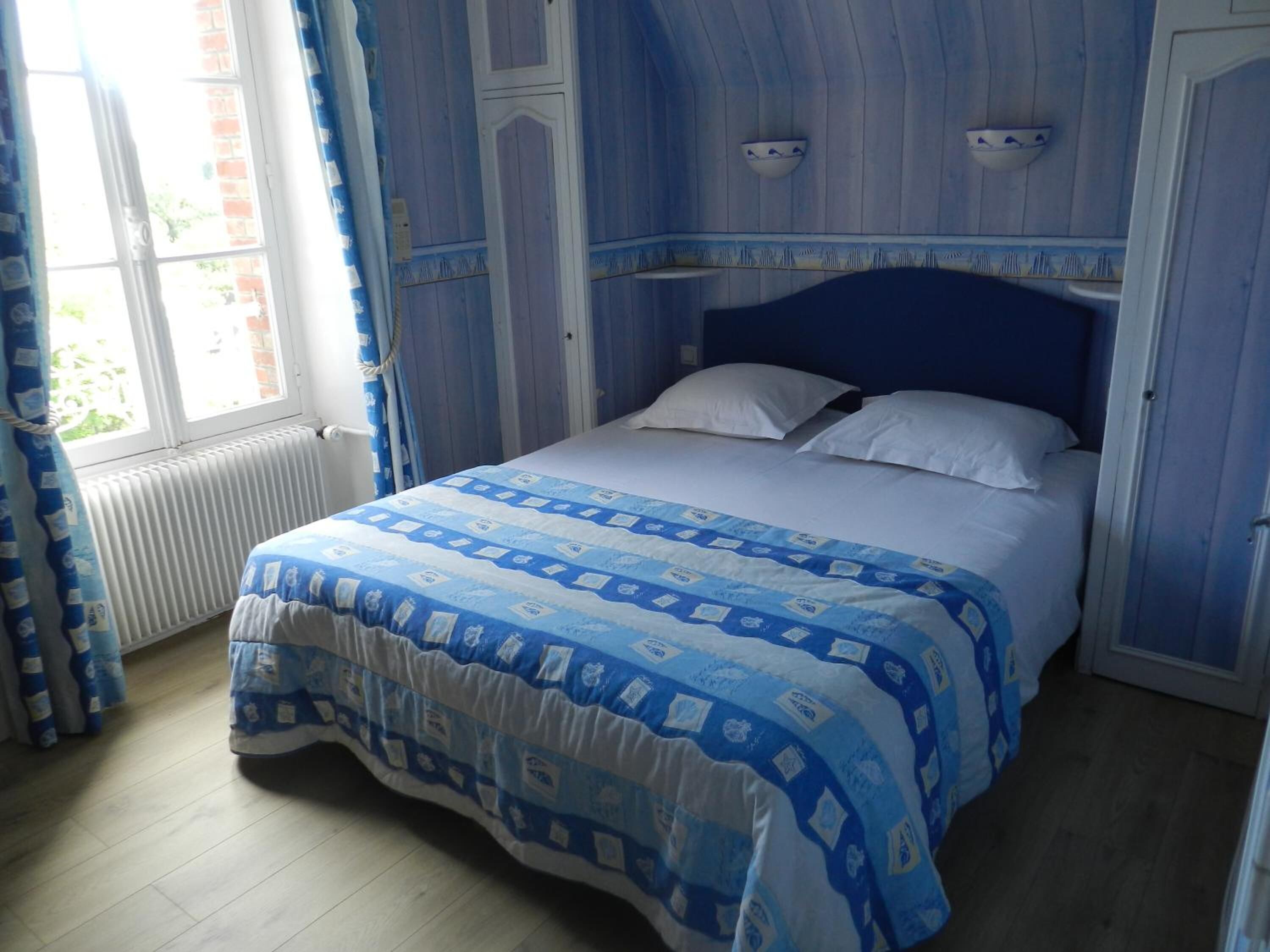 Ein Schlafzimmer mit Bett, Vorhängen und einem Fenster.