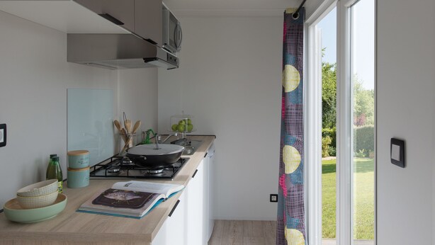 A modern kitchen with a wooden countertop, a gas stove, and a window with a view of the garden. - O2 camping (Longueville)