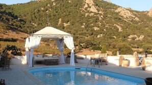 A swimming pool with a white gazebo, outdoor furniture, and a mountainous backdrop. - Casa Alianda (Telti)
