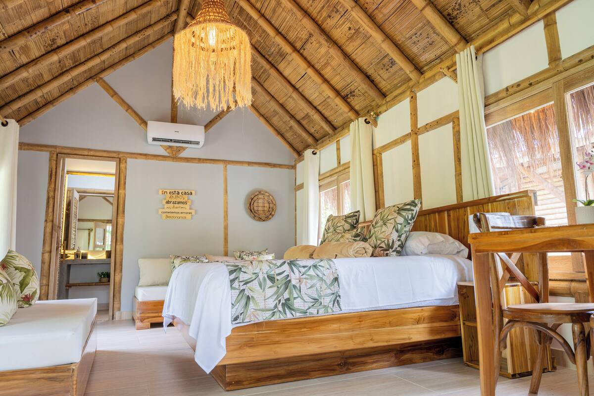 A wooden-framed bedroom with a bed, a chair, a desk, and a hanging light fixture.