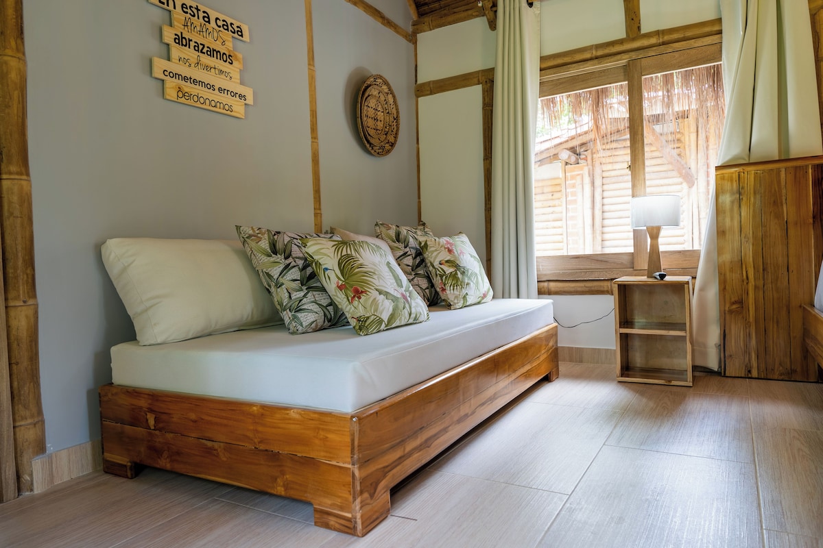 Una cama de madera con colchón blanco y almohadas estampadas, una escalera de madera y un panel de madera en la pared.