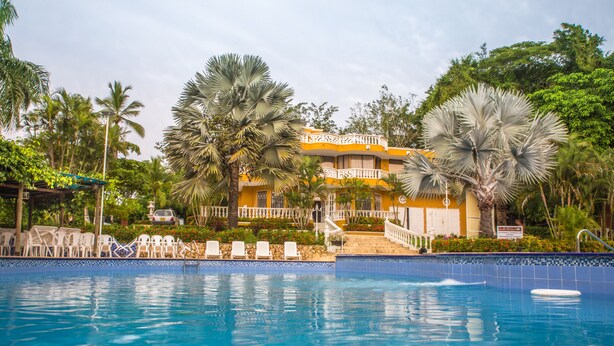 Un hotel rodeado de palmeras y un jardín, con piscina.