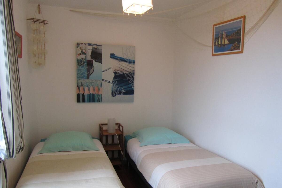 A bedroom with two beds, a small wooden table, and wall art.