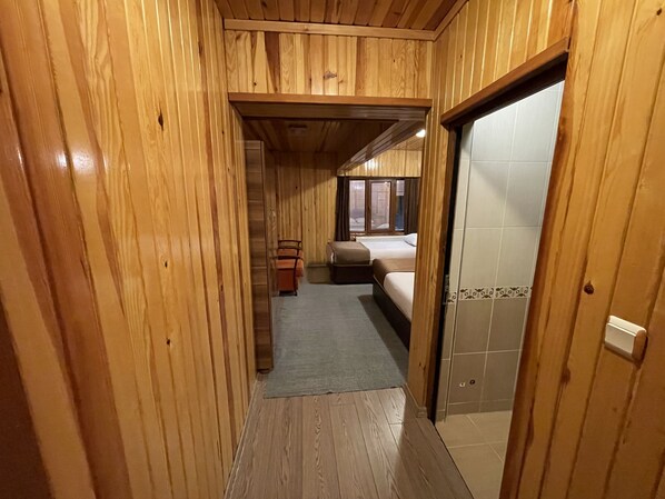 A wooden interior with a bed, a small table, and a window. - Ozkan Hotel (Çaykara)